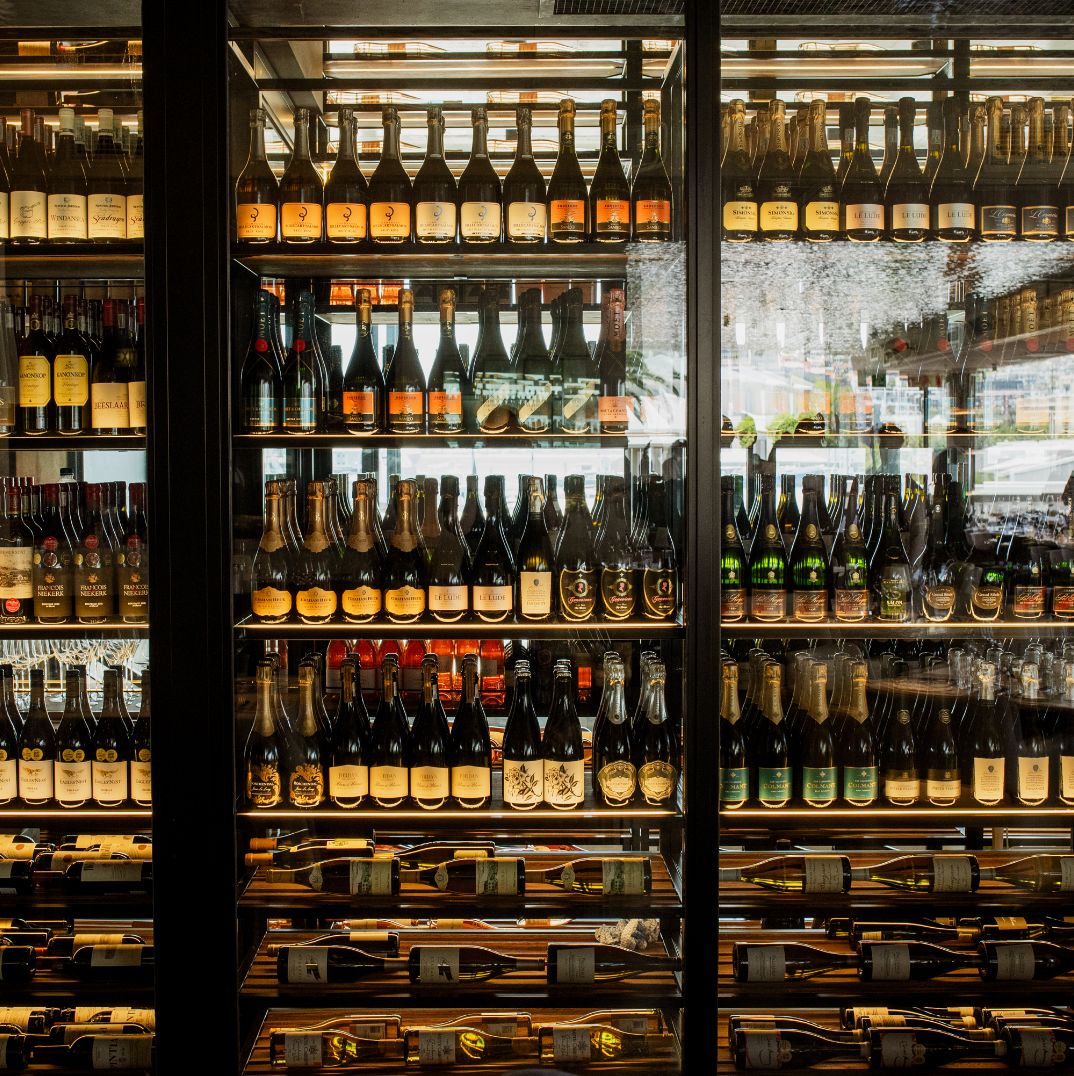 A well-stocked, floor-to-ceiling wine cellar at Marble's rooftop bar in Cape Town, showcasing a wide selection of wines and champagnes