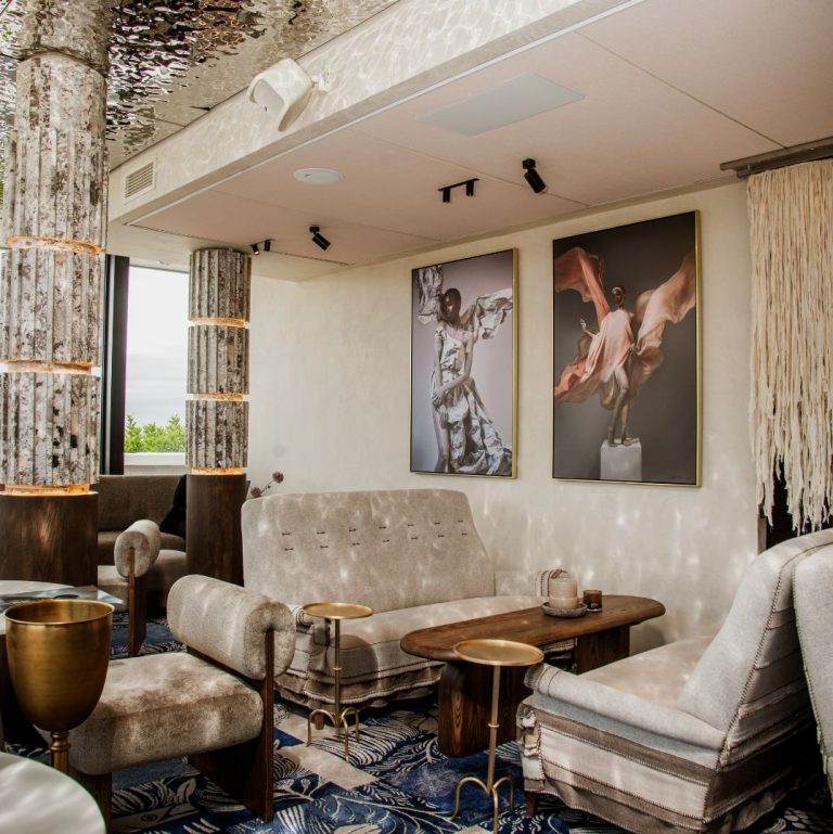 Stylish lounge area at Marble's rooftop bar at the V&A Waterfront, with unique furniture, striking artwork, and a detailed patterned rug