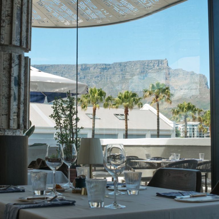 An elegant dining table with a breathtaking view of Table Mountain, highlighting the ambiance at Marble's rooftop bar at the V&A Waterfront
